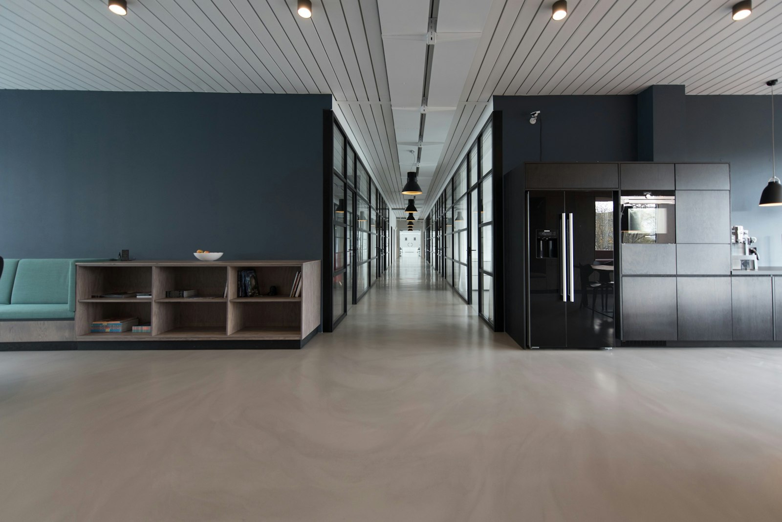 Open-plan office interior with glass-walled rooms along a corridor