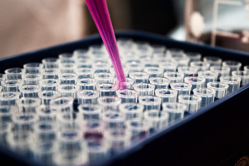 Laboratory pipette dispensing liquid into a tray of sample vials